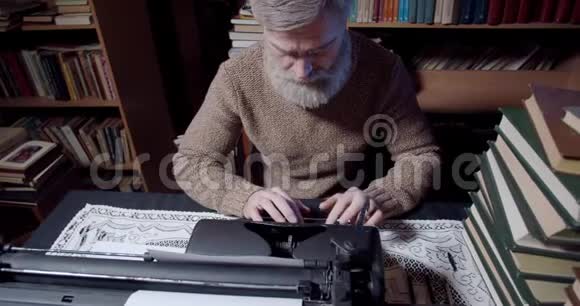 一位老作家用老式打字机从图书馆工作的录像4k视频的预览图