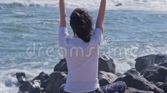 女人在海洋海岸的岩石上沉思视频的预览图