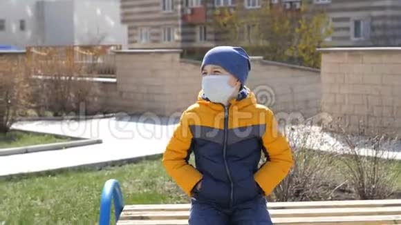 一个戴医疗面具的男孩坐在街上的长凳上的肖像视频的预览图