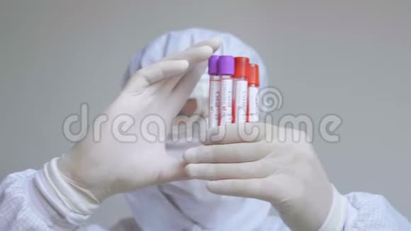 医生戴着流感面罩和防护手套拿着一个带有冠状病毒血样的试管预防流感视频的预览图