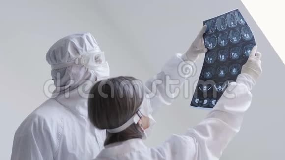 医生站在白色背景下检查X光检查一名Covid19病人在诊所的肺炎冠状病毒视频的预览图