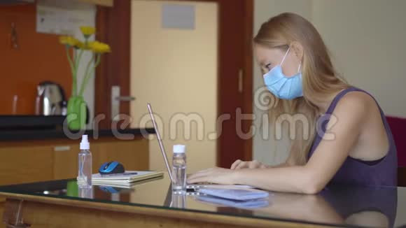 一位戴着医用面罩的年轻女子在冠状病毒自我隔离期间在家工作远程工作概念视频的预览图