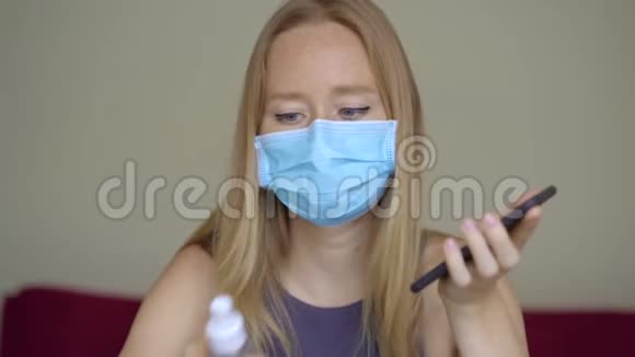 一位戴着面罩的年轻女子在冠状病毒自我隔离期间在家工作她用酒精消毒器视频的预览图