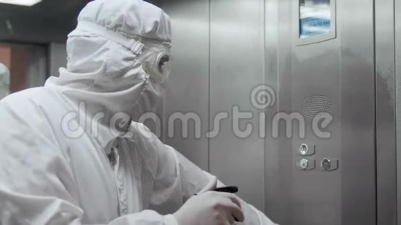 冠状病毒感染带防护面罩和服装的辅助医务人员用喷雾器消毒电梯视频的预览图