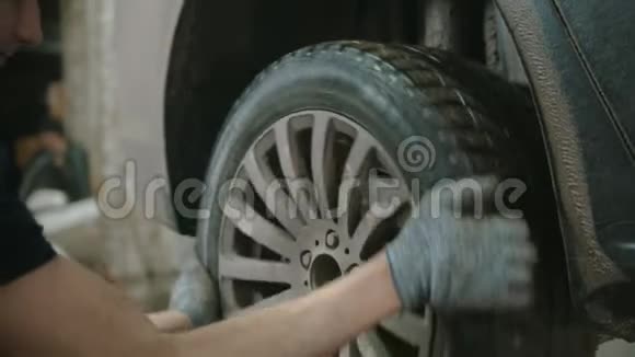 汽车修理店年轻人在汽车上旋转轮子视频的预览图