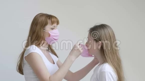 工作室里的年轻母女在白色背景的隔离期间戴上口罩以保护视频的预览图