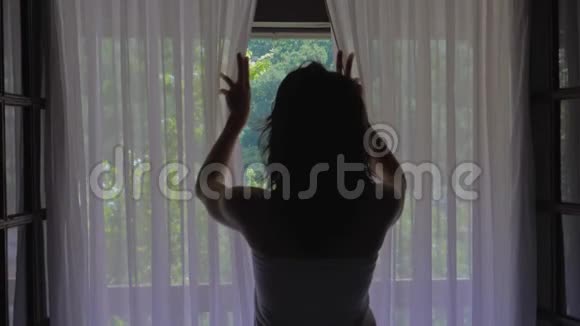 卧室里的女人早上打开窗帘和窗户视频的预览图