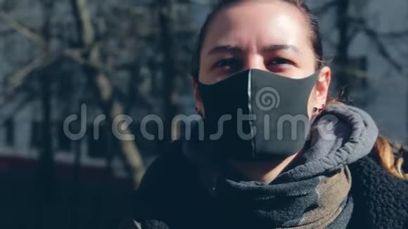 一个戴着黑色防护面罩的女孩在看镜头时呼出烟雾在大街上在视频的预览图