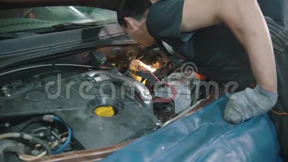 汽车修理店青年工人在车盖下检查汽车视频的预览图