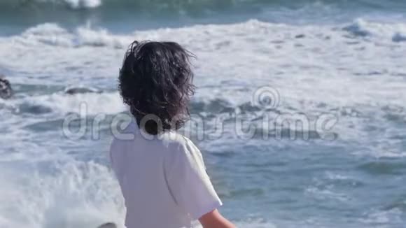 年轻女子在海边的岩石上沉思视频的预览图