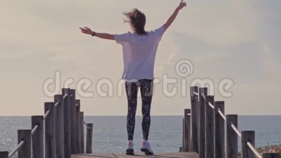 欢乐和跳跃的女人在海边沿着人行道奔跑视频的预览图