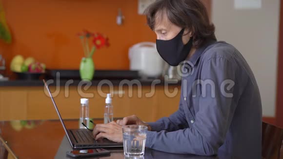 一个戴着面罩的年轻人在家中工作进行电晕病毒自我隔离视频的预览图