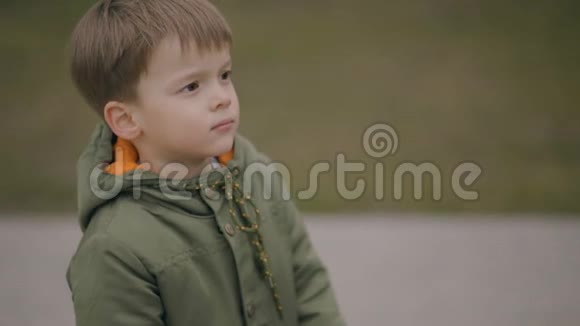 严肃的小男孩穿着绿色的春天夹克站着看着镜头视频的预览图