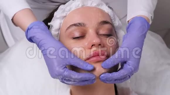 化妆程序面部按摩美容院的女人脸上戴着面具面罩应用视频的预览图