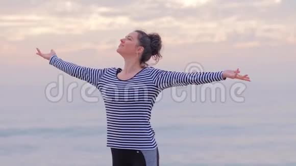 海滩上穿条纹衬衫的快乐女人享受日落视频的预览图