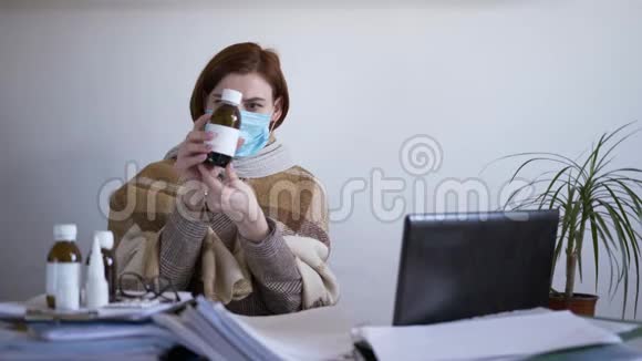 办公室里的病戴着医用口罩的年轻女员工在便携式电脑上工作检查医疗情况视频的预览图