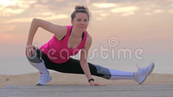 穿着健身服的女人在海边做伸展运动视频的预览图