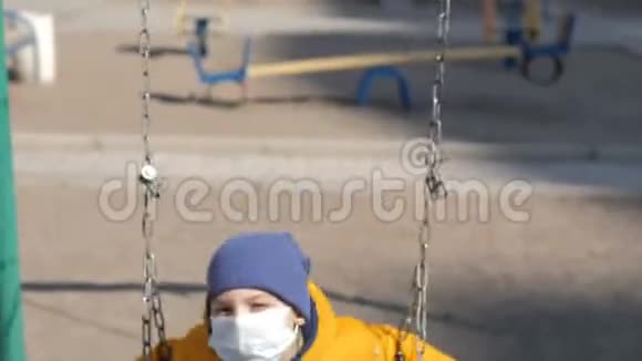 大流行病期间小男孩坐在外面荡秋千戴着织物面罩视频的预览图