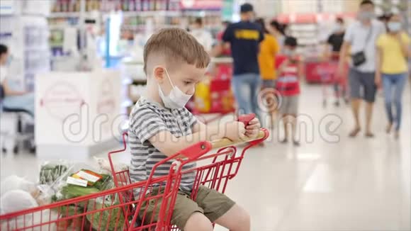 妈妈带着孩子在超市购物孩子戴着防毒面具孩子坐在超市里视频的预览图