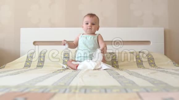 婴儿坐在床上玩白色餐巾纸情绪化的孩子第一个快乐是简单的事情视频的预览图