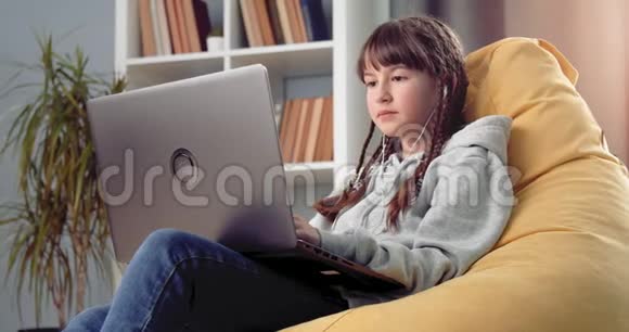 可爱的女孩在家用笔记本电脑远程学习视频的预览图