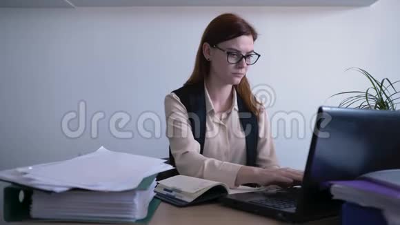 忙碌的工作日里戴着眼镜的漂亮女人看着屏幕把信息写到笔记本上视频的预览图