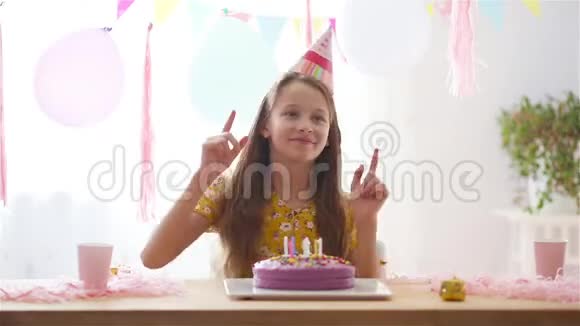 白人女孩梦幻般地微笑着看着生日彩虹蛋糕带有气球的节日色彩背景视频的预览图
