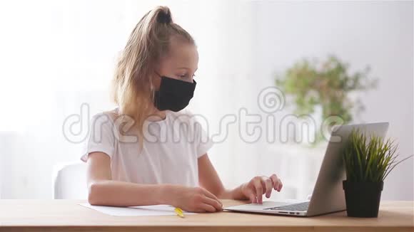 严肃的女学生坐在桌旁拿着笔记本电脑和课本做作业视频的预览图