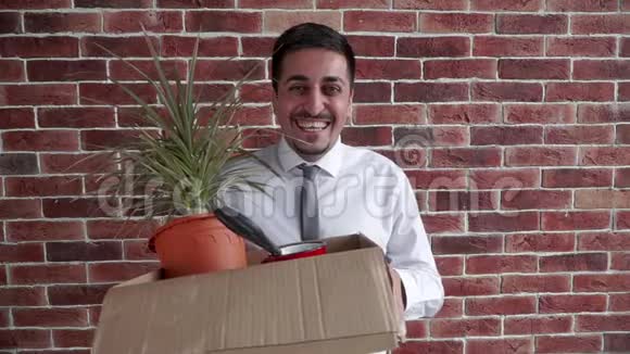一个快乐的被解雇的上班族笑着拿着一盒东西和一朵花然后突然心烦意乱视频的预览图