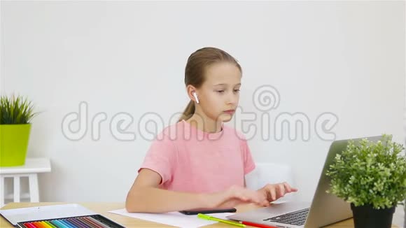严肃的女学生坐在桌旁拿着笔记本电脑和课本做作业视频的预览图