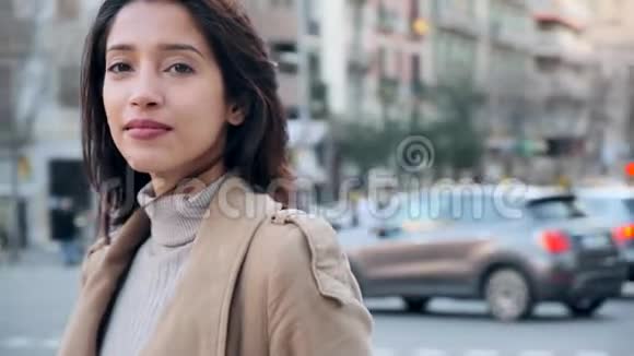 漂亮的年轻女人在街上散步时看着相机背景中城市交通视频的预览图
