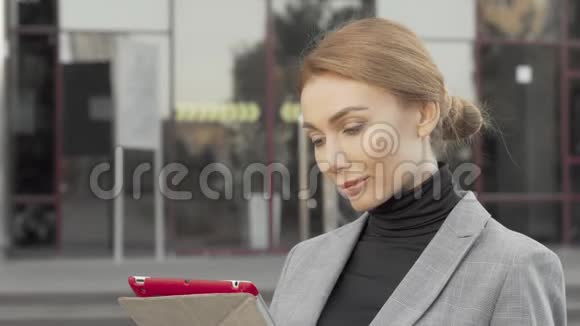 在城市户外使用数码平板电脑的漂亮女商人视频的预览图