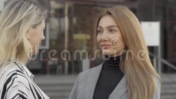 两位女同事在户外愉快地交谈视频的预览图