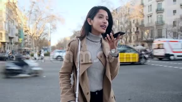 漂亮的年轻女人站在街上用手机和免费系统说话视频的预览图