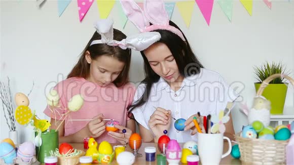 妈妈和她的小女儿画鸡蛋为复活节做准备的幸福家庭视频的预览图