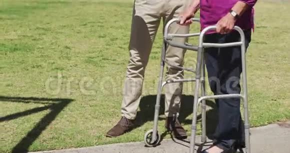 医生在一个养老院的公园里和一个老女人散步视频的预览图