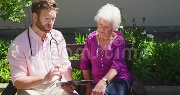 医生和一个老女人在一个养老院的公园里视频的预览图