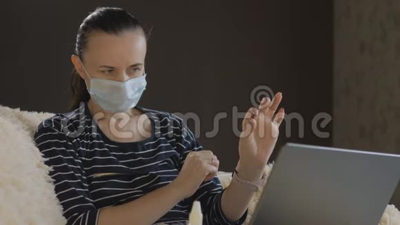 那个戴着防护面罩的女人在笔记本电脑上的视频会议上咨询你的医生吃药视频的预览图