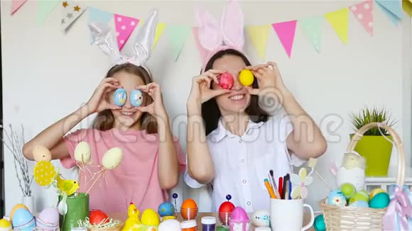 妈妈和她的小女儿画鸡蛋为复活节做准备的幸福家庭视频的预览图