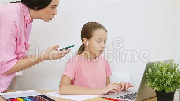 小女孩在家里电脑学习母亲帮助女儿完成任务在线培训儿童学习视频的预览图