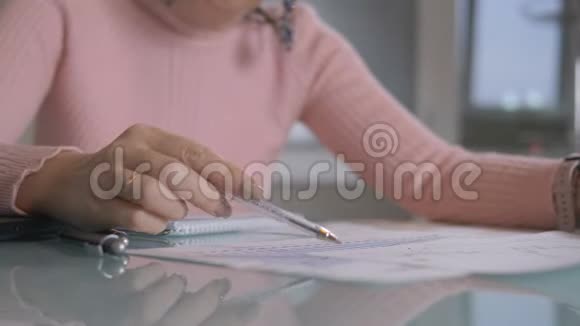 靠近一个坐在桌子旁用图表工作的女人视频的预览图
