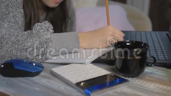 一个十几岁的女孩在家上学女孩在计算器上计算一个数字并将结果写在笔记本上特写视频的预览图