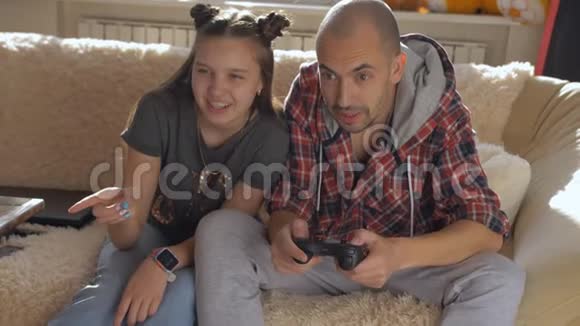 一个父亲和一个十几岁的女儿在家里一起在控制台上玩视频的预览图