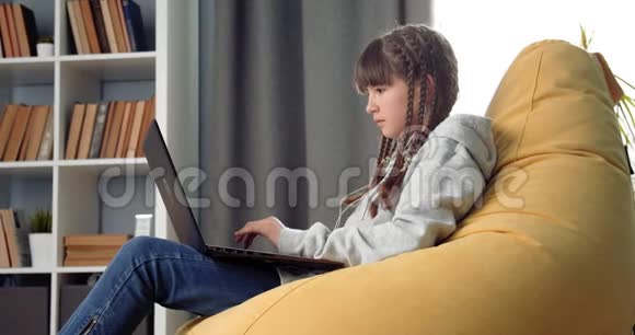 小女孩在家里用笔记本电脑做作业的侧视图视频的预览图