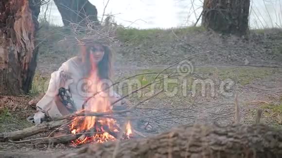 一个女巫的年轻女子坐在树林中的火前视频的预览图