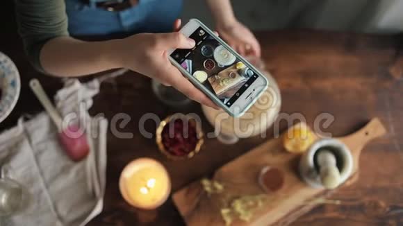 一个年轻女孩在电话里拍照她的厨房里有她的熟食背景模糊特写视频的预览图
