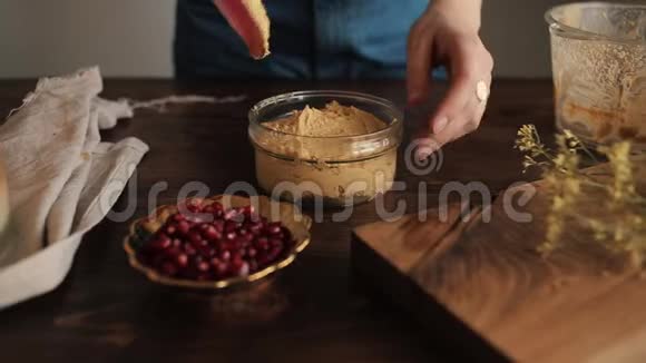 一个女孩用厨房的硅胶铲子把煮熟的健康自制的鹰嘴豆泥放在玻璃碗里特写视频的预览图
