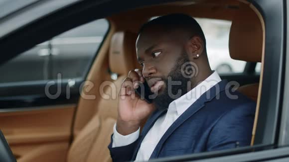 一个黑人在车上打电话坐在豪华轿车前排的男人视频的预览图