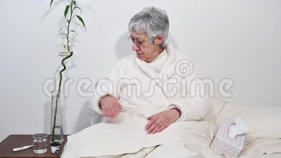 生病的老年妇女吃药从手上的瓶子里倒药丸视频的预览图