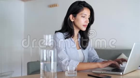 优雅的年轻女商人在办公室里用电脑工作时收到一条电话信息视频的预览图